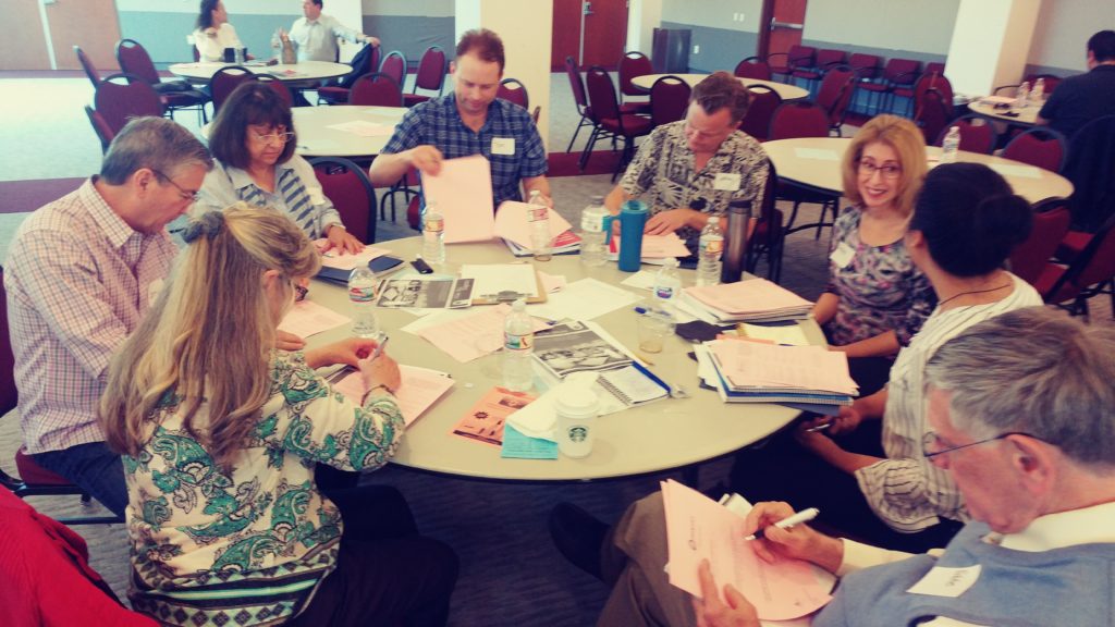 Participants actively collaborating at a round table, reviewing materials and sharing ideas during a workshop session.